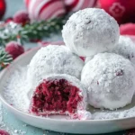 A plate of decadent red velvet snowballs dusted with powdered sugar, garnished with mint leaves.