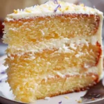 A beautifully decorated vanilla cake with white frosting and colorful sprinkles on a wooden table