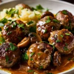 Delicious Salisbury steak meatballs topped with rich mushroom gravy, served on a white plate with parsley garnish