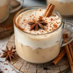 A steaming cup of vanilla cinnamon milk tea topped with a sprinkle of cinnamon and a cinnamon stick