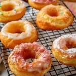 A plate of freshly made air fryer biscuit donuts topped with colorful sprinkles and drizzled with icing.