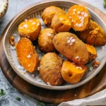 Golden brown air fryer sweet potato fries served with a dipping sauce on a wooden table