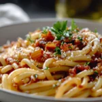 A bowl of caramelized onion pasta chili topped with fresh herbs and cheese