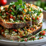A bowl of creamy olive tapenade topped with crumbled goat cheese, garnished with fresh herbs.